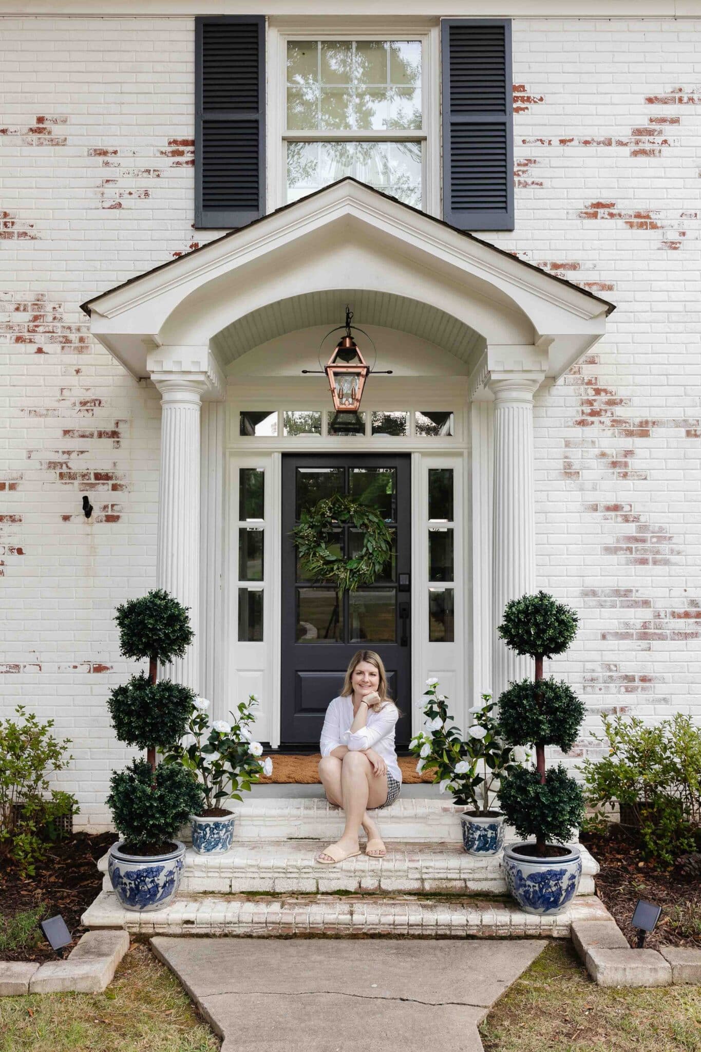 colonial front door makeover with limewashed brick, blue and white planters, and copper gas lantern lookalike