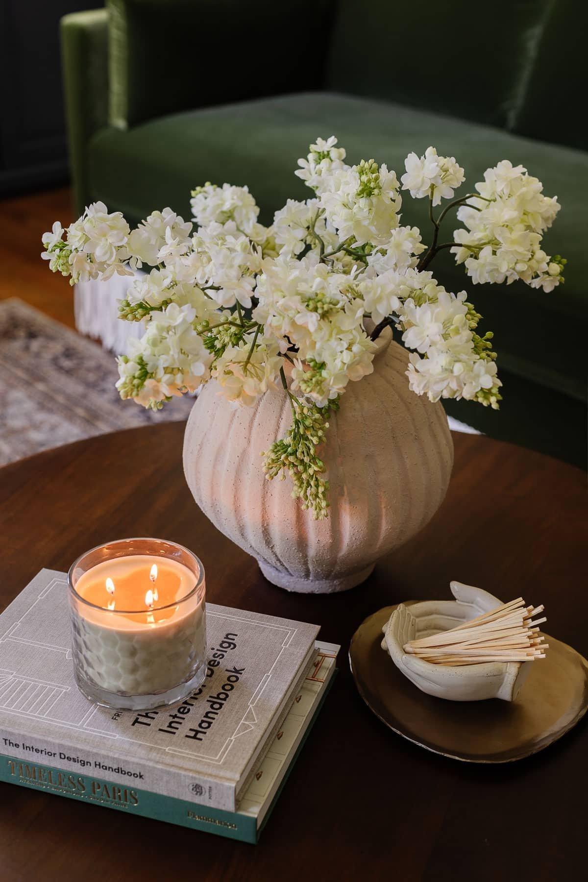 coffee table decor with vase of flowers, coffee table books, candle, tray, and bowl of matches