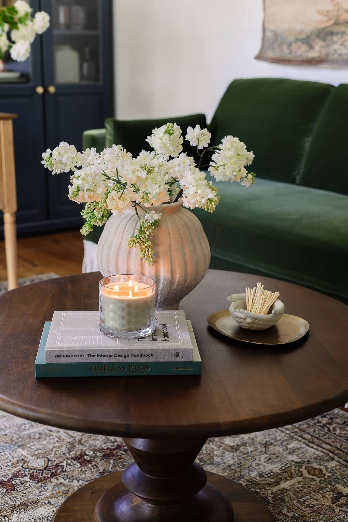 coffee table decor with vase of flowers, coffee table books, candle, tray, and bowl of matches