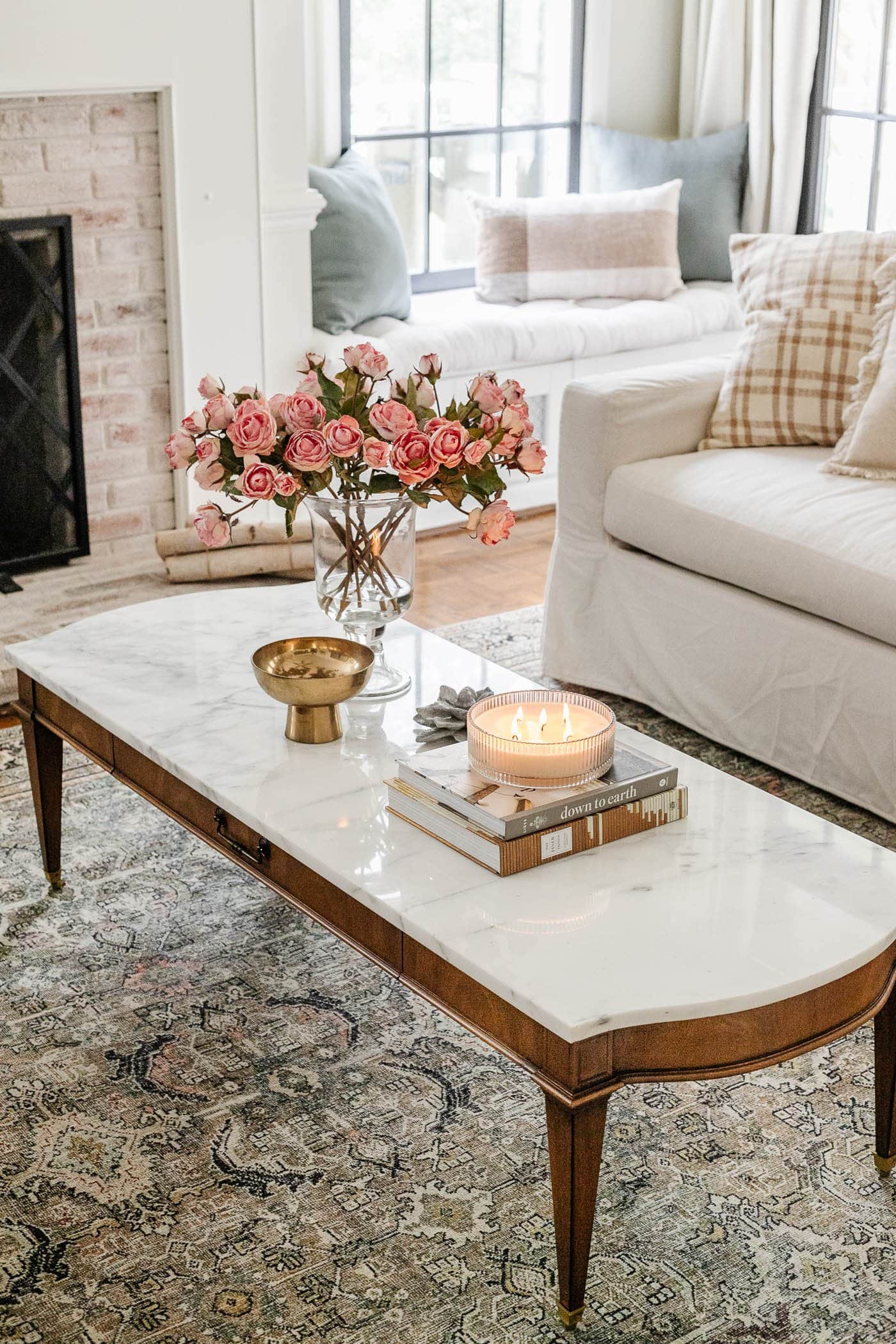 marble top coffee table with vase of roses, stack of books, and candle