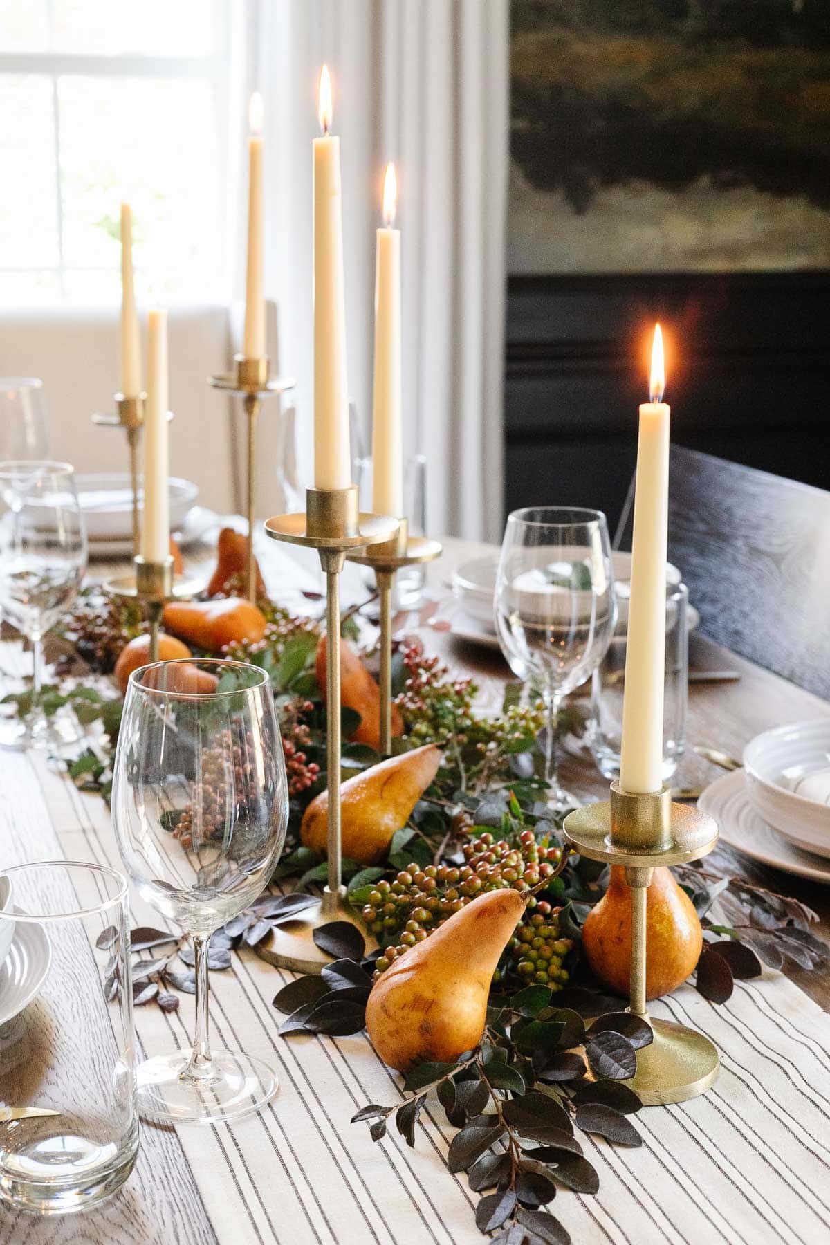 foraged fall centerpiece with cut leaves, berries, pears, and brass taper candles