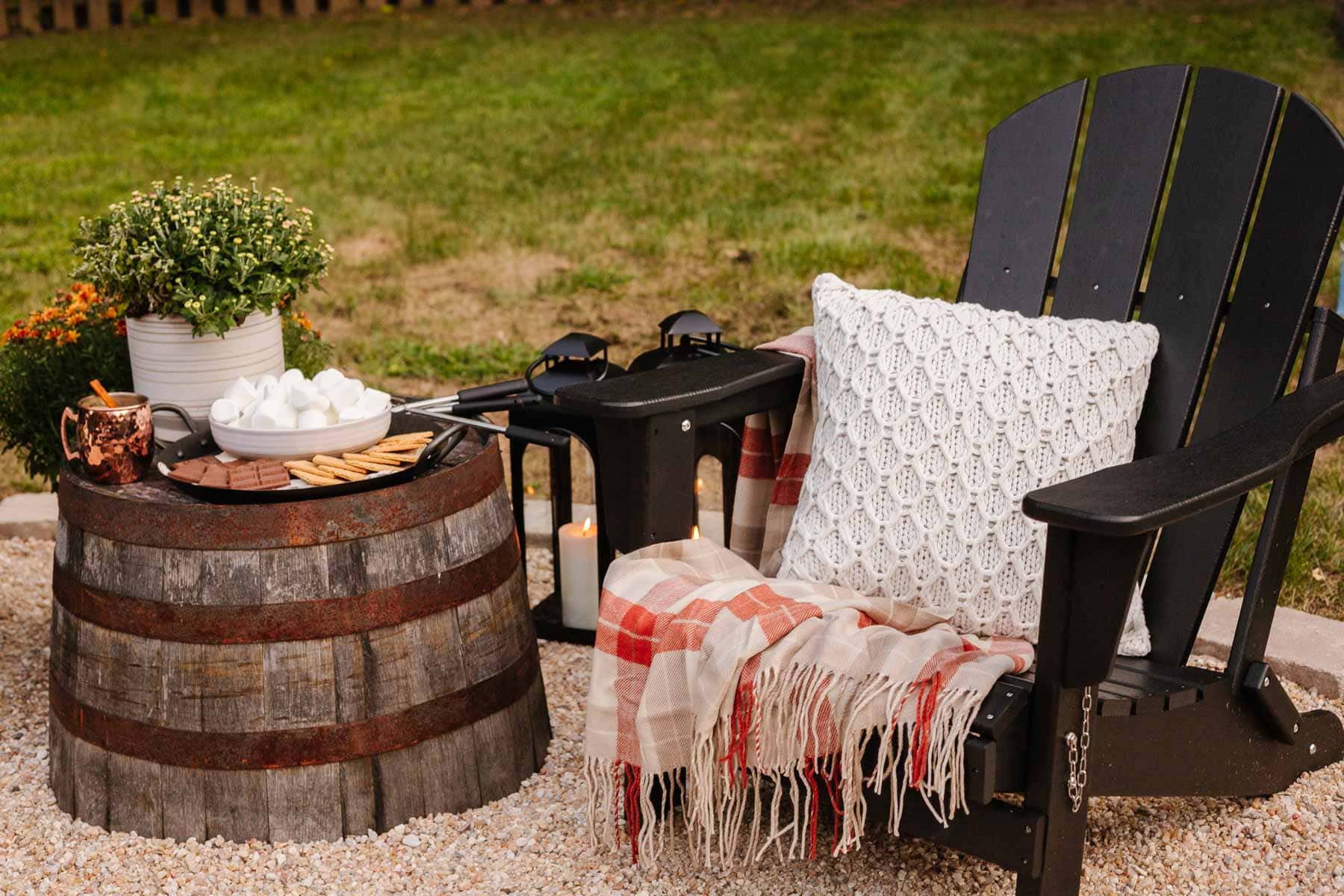 adirondack chair with blanket, pillow, and barrel table with s'mores ingredients