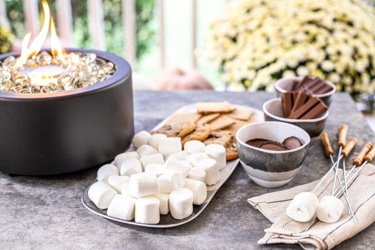 s'mores ingredients next to a tabletop fire pit