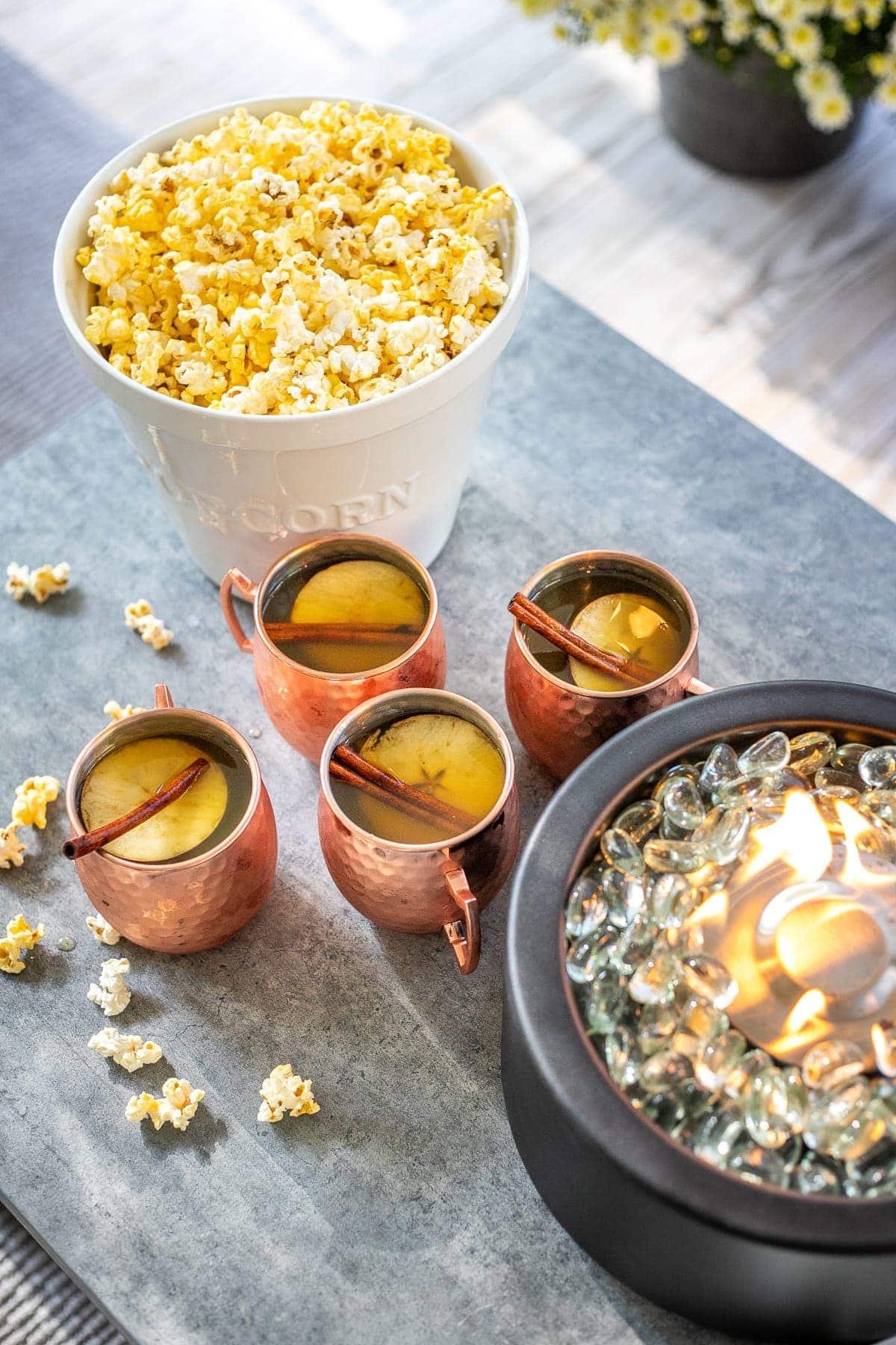 bucket of popcorn and copper mugs of apple cider 