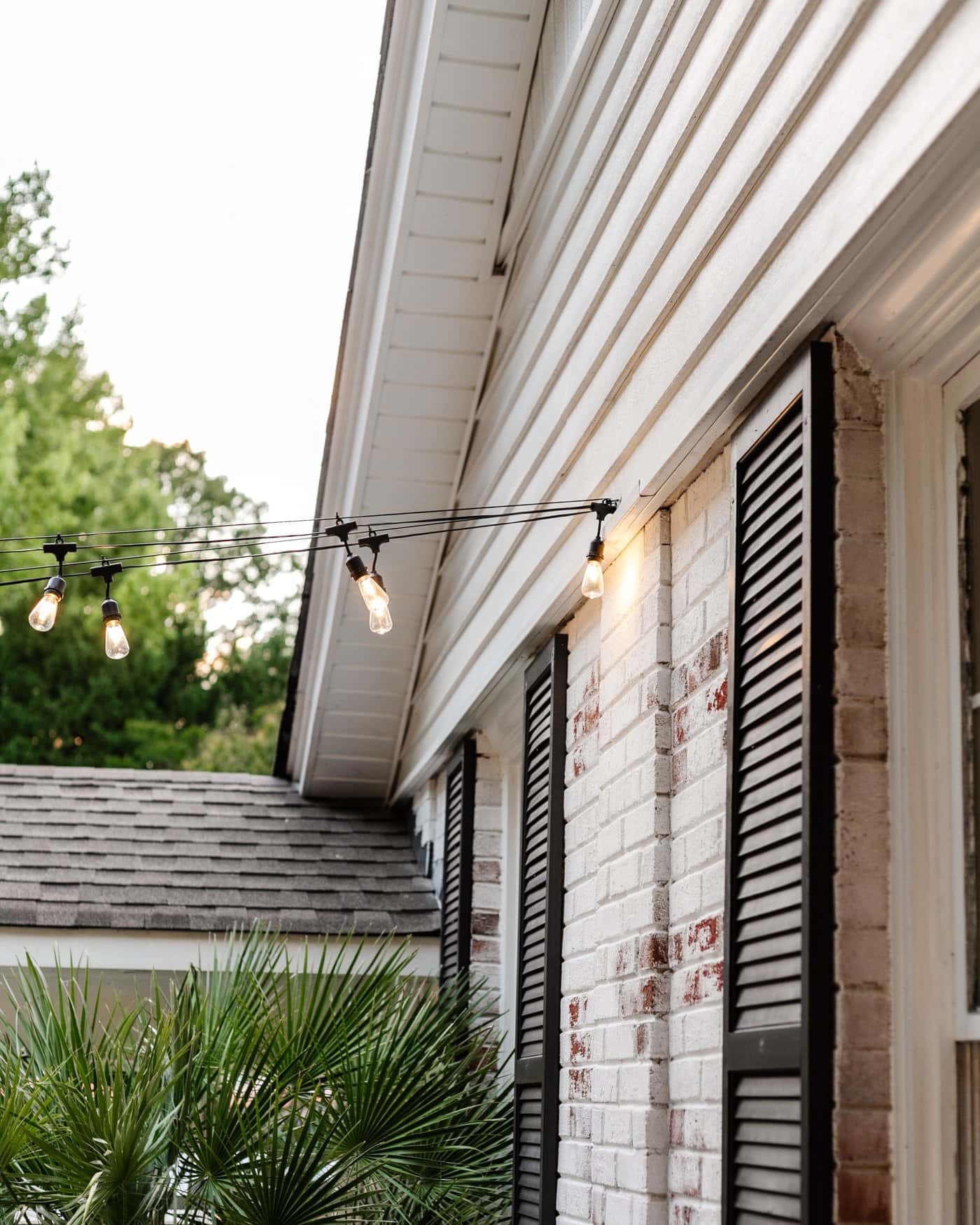 string lights attached to house siding in a backyard