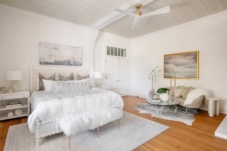 White bench in front of bed in open, airy living room.