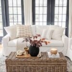 fall pillows a couch in a living room with fall leaves in a vase on a woven coffee table