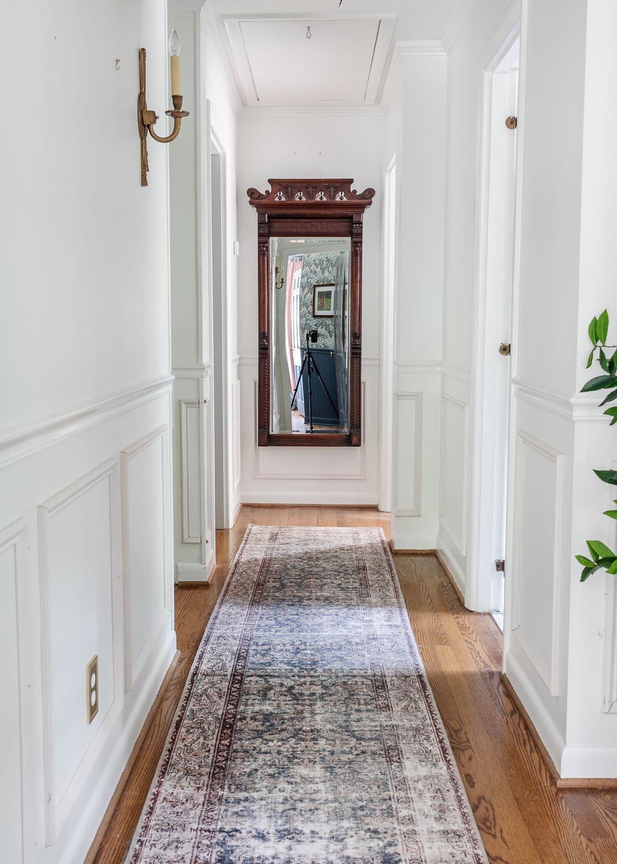 white hallway with wood floors and mirror