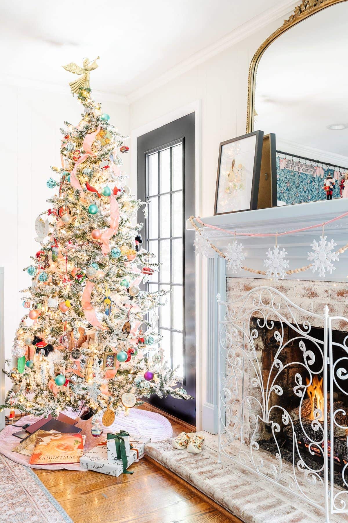 flocked Christmas tree in playroom with homemade ornaments and pink ribbon beside a fireplace